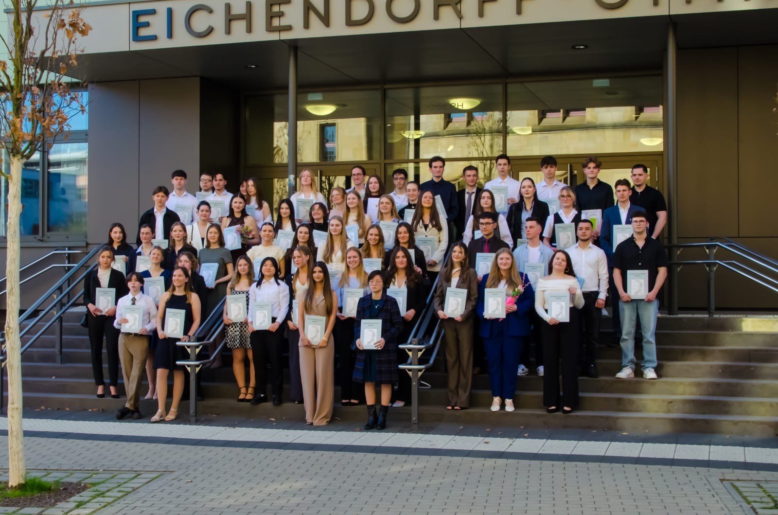 Stilvoller Abschied vom Eichendorff-Gymnasium Koblenz: 74 Abiturientinnen und Abiturienten sagen nach erfolgreichen Prüfungen Lebewohl und stellen sich vor ihrer Schule zu einem Erinnerungsfoto zusammen.	